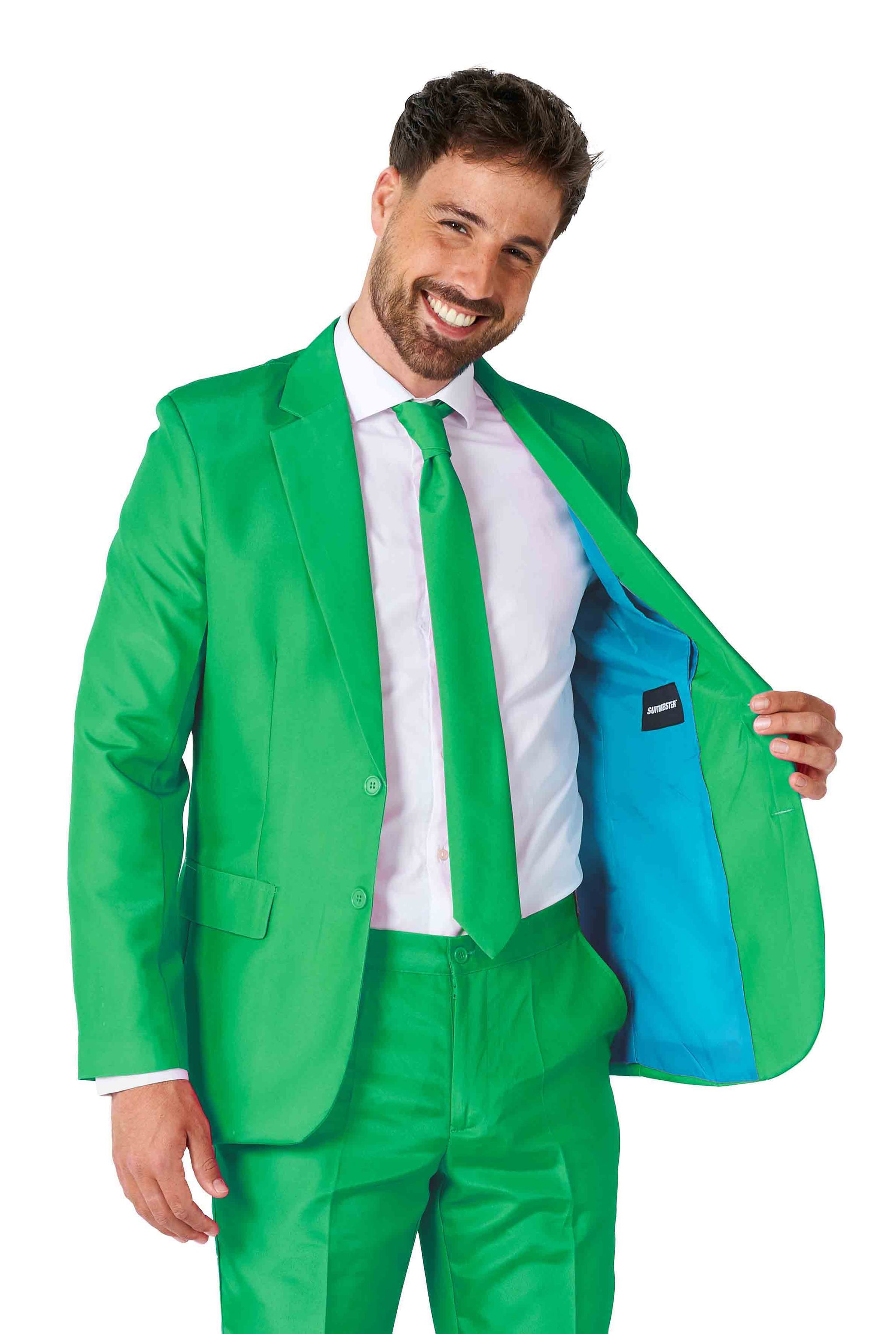 A man dressed in a Suitmeister Solid Green Suit, complete with a matching tie and white shirt, smiles as he reveals the jacket's blue lining.