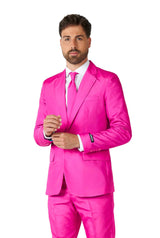 A man with brown hair and a beard stands against a white background, wearing the Suitmeister Solid Pink suit, complete with a matching tie over a white shirt.