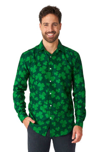 A man is smiling while wearing the "St. Pats Green - St Patrick's Day shirt" by Suitmeister, featuring a shamrock pattern, paired with dark pants. He has one hand in his pocket against a plain white background.