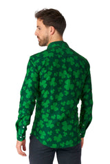 The man with short hair is modeling the Suitmeister "St. Pats Green - St Patrick's Day shirt," which features a design of light green shamrocks on a dark green background. He is standing with a slight turn to the side, providing a view of the shirt’s back against a plain white background.