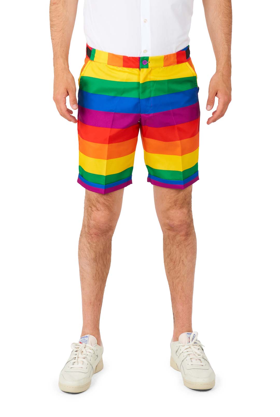 A person is dressed in the colorful Suitmeister Rainbow suit, featuring vibrant rainbow-striped shorts paired with a white shirt. They are also sporting white sneakers, and the image captures them from shoulders to knees against a plain white background.