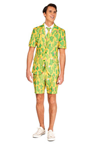 A person is standing and smiling in the Sunny Yellow Cactus - Summer Suit by Suitmeister, showcasing a vibrant bright yellow design with a green cactus pattern. The ensemble features short sleeves and matching shorts, complemented by a white shirt and tie, along with white sneakers.