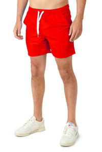 A person wearing the Superman outfit from Suitmeister stands against a solid white background, with a focus on the red shorts with white drawstrings and the matching white sneakers.