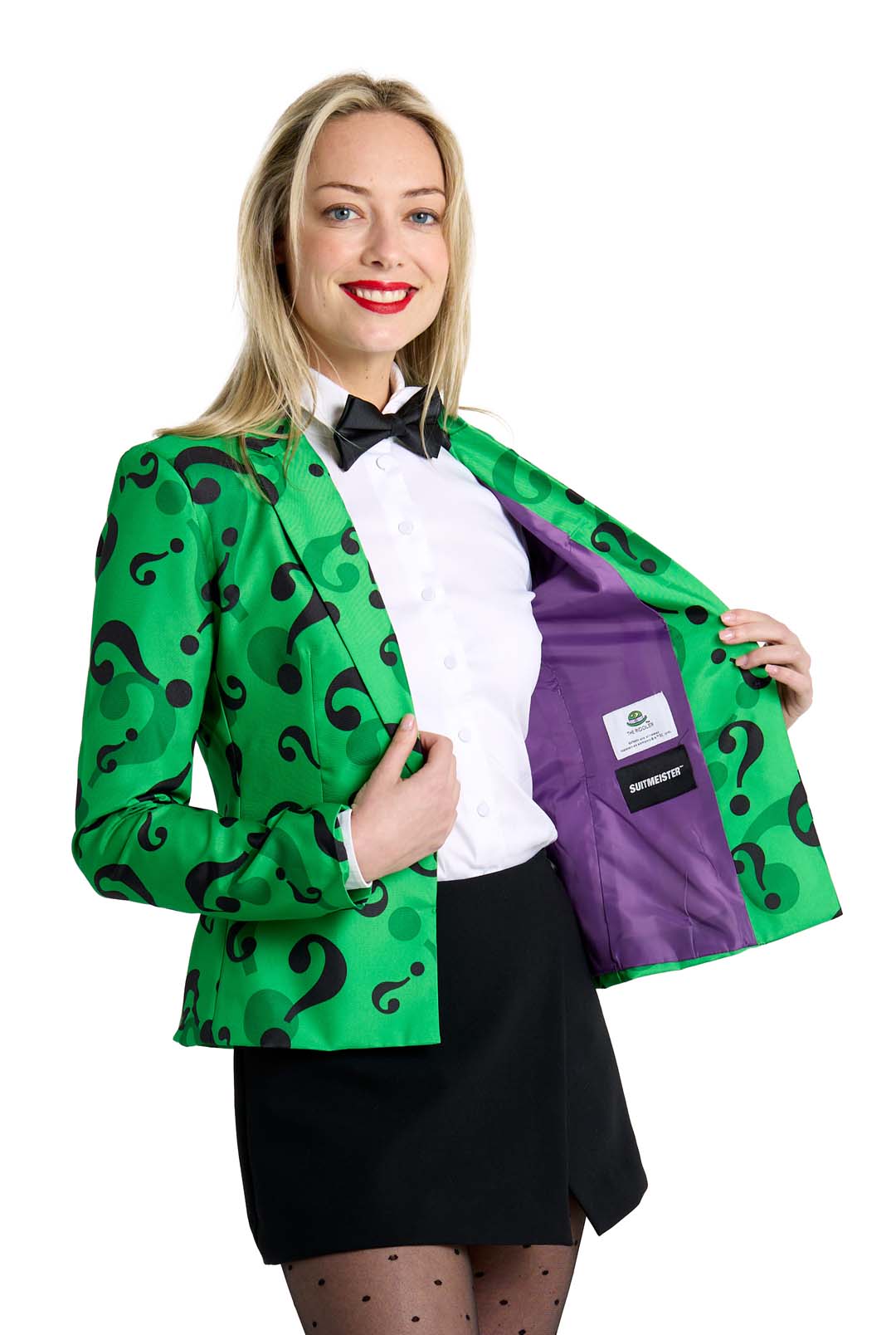 Sporting a vibrant green blazer adorned with black question marks, known as The Riddler Jacket by Suitmeister, a person in a white shirt and bow tie is revealing the blazer's striking purple lining. Completing their ensemble with a black skirt and polka dot stockings, they stand against a pristine white background.