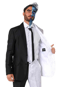 A man is dressed in the Suitmeister Two Face costume, characterized by a half black and half white design. The left side is formal black, while the right side of the suit and matching face paint burst with vibrant colors like blue. He is holding open the jacket on the white side.