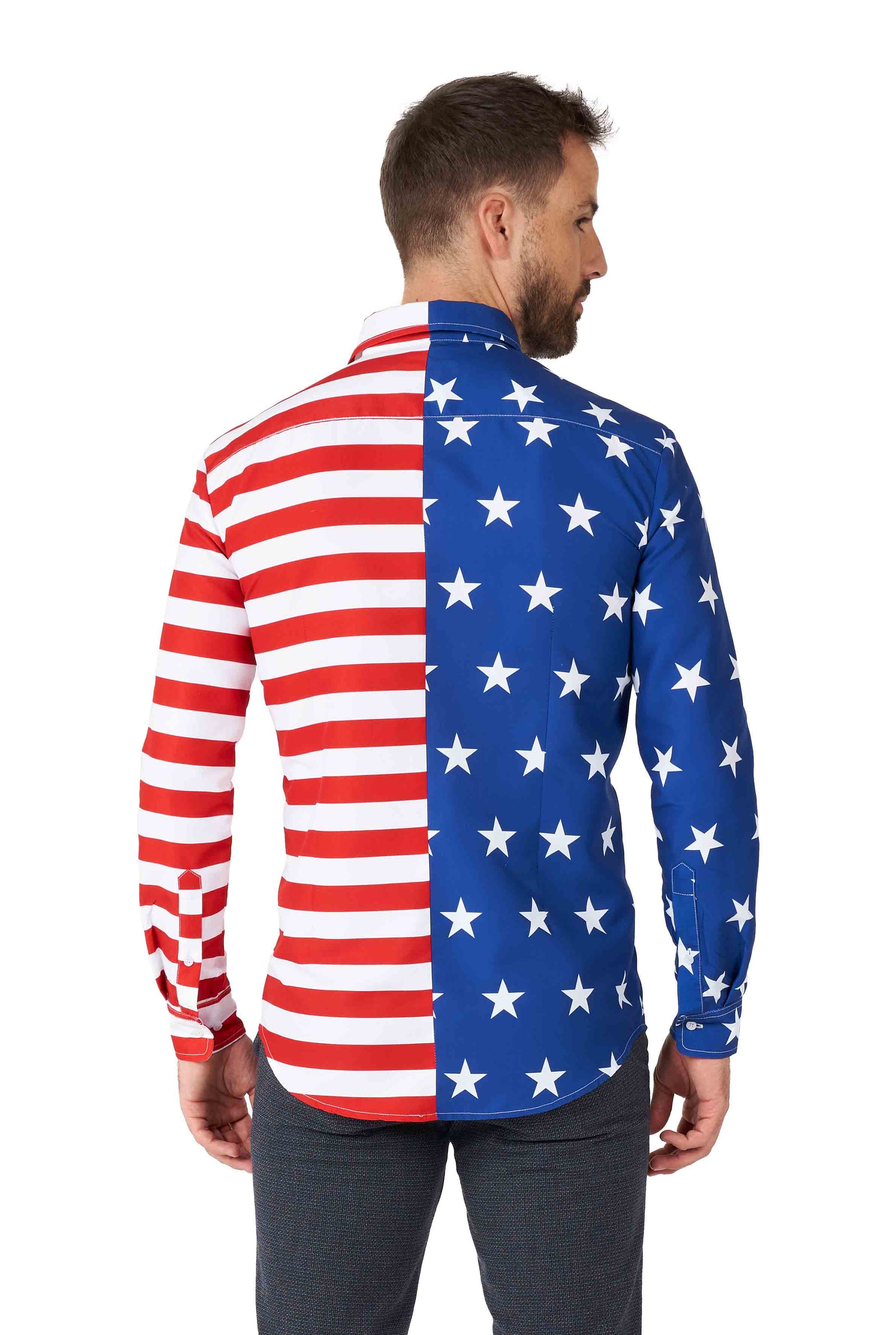 A man with short brown hair and a beard is wearing a Suitmeister USA Flag Shirt, featuring an American flag pattern. The right side showcases red and white stripes, while the left side displays blue with white stars. He is facing away from the camera.