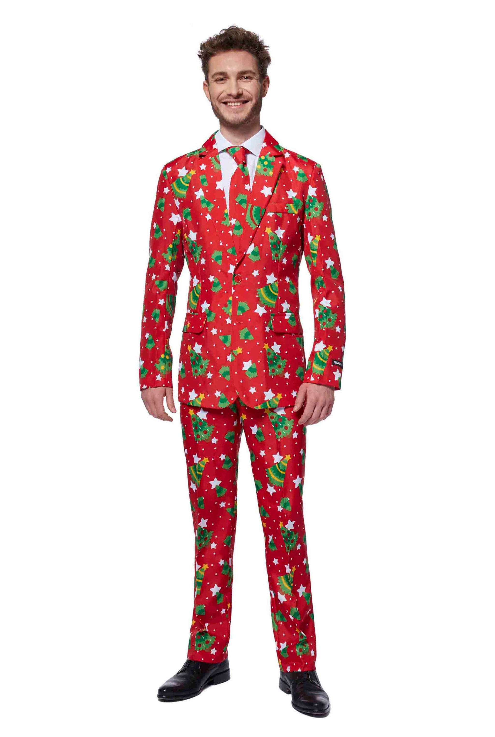 A man dressed in a Suitmeister Christmas Trees Stars Red suit, featuring festive patterns of green trees and white snowflakes, stands smiling against a white background.