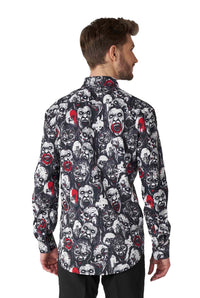 A man with short brown hair, facing away, is wearing the "Zombie Characters - Zombie shirt" by Suitmeister, a long-sleeved top adorned with a vibrant pattern of expressive cartoon-style faces in black, white, and red. He is also dressed in black pants.